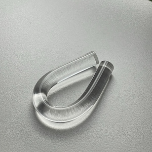May include: A clear plastic ring with a smooth, rounded surface. The ring is made of two pieces that are joined together.