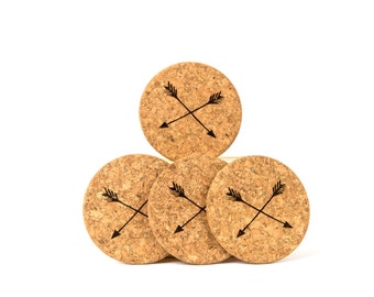 May include: Four cork coasters with a black arrow design. The coasters are stacked in a pyramid shape.