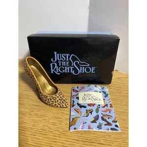 May include: A miniature leopard print high heel shoe figurine with a gold interior, accompanied by a black box labeled Just The Right Shoe and a matching informational booklet featuring various shoe illustrations and the Willitts Designs logo.
