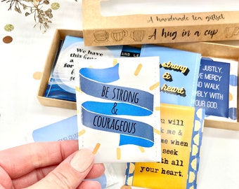 Può includere: Un set regalo di bustine di tè con messaggi ispiratori. Le bustine di tè sono confezionate in una scatola marrone con una finestra. Le bustine di tè sono decorate con disegni blu e gialli. I messaggi sulle bustine di tè includono "Sii forte e coraggioso", "Forte e cuore", e "Giustamente. Abbi misericordia e cammina umilmente con il nostro Dio."