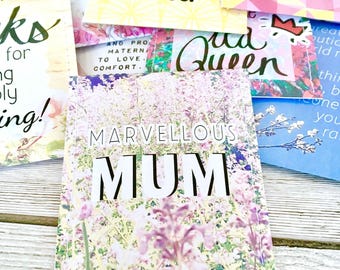 Può includere: Una collezione di biglietti di auguri colorati con vari disegni floreali e geometrici. Le carte presentano frasi come "Mamma meravigliosa", "Ti amo mamma" e "Ciò che sono, mi hai aiutato a essere".