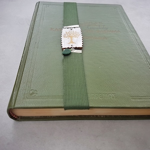 May include: A green leather-bound book with a bookmark featuring a carved wooden tree design and green accents. The book has the word "remarkable" embossed on the cover.