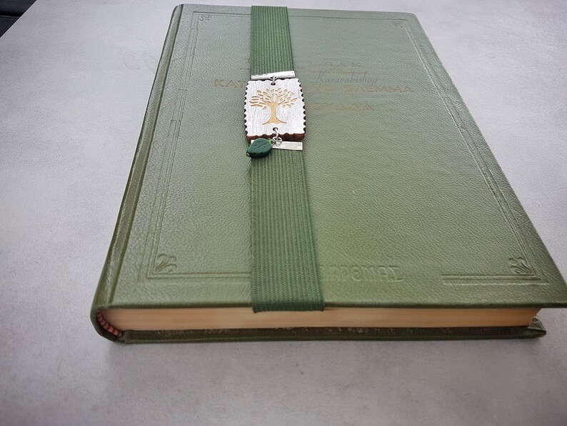May include: A green leather-bound book with a bookmark featuring a carved wooden tree design and green accents. The book has the word "remarkable" embossed on the cover.