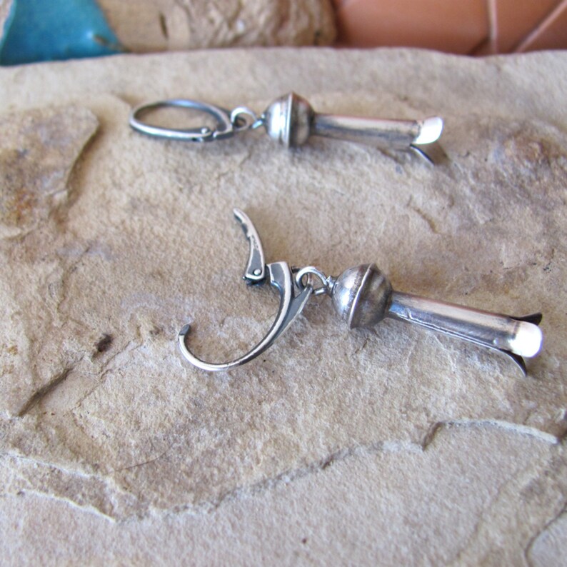May include: A pair of silver earrings with a teardrop-shaped pendant. The earrings have a lever back closure.