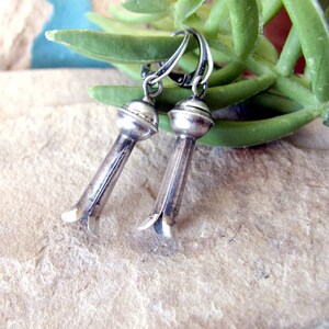 May include: A pair of silver earrings with a flower-shaped design. The earrings are hanging from a silver hoop.