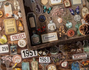 May include: A selection of vintage-style stickers with botanical and butterfly motifs. The stickers feature labels, bottles, and floral designs, with text like "Fly," "Blessed," and "Natural Beauty." The colour palette includes browns, blues, and yellows.