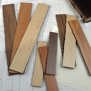 May include: A collection of wooden bookmarks in various shades of brown and tan. Each bookmark has a unique, natural edge. The bookmarks are arranged on a vintage paper background, suggesting a handcrafted or artisanal theme.
