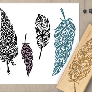 May include: An image features five decorative feather designs. Four are printed on white paper in black, teal, and lavender. A wooden stamp with a feather design is also present. The feathers have intricate patterns.