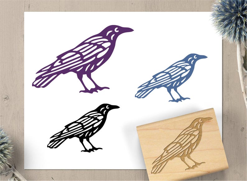 May include: A collection of raven illustrations in purple, blue, and black, alongside a wooden stamp with a raven design. The raven images are detailed with wing and body patterns, suitable for art or craft projects.