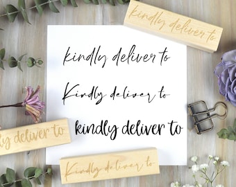 May include: A white paper with the words "kindly deliver to" in a handwritten font. Wooden stamps with the same text are also present. The background is a light wood surface with floral and greenery accents.