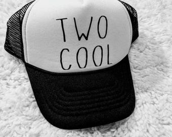 Könnte beinhalten: Schwarz-weiße Trucker-Mütze mit dem Schriftzug "TWO COOL" in schwarzer Schrift. Die Mütze hat eine weiße Front, einen schwarzen Schirm und eine schwarze Netzrückseite.