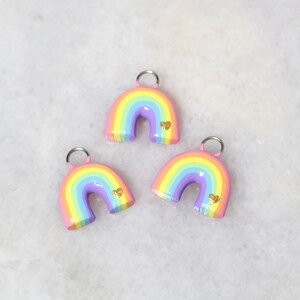 Three pastel rainbow arch charms with tiny gold hearts.