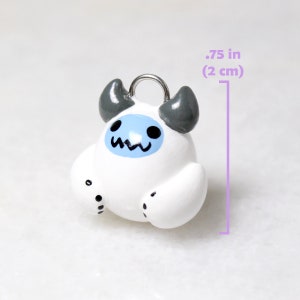 A yeti charm next to a measurement ruler that reads: .75 inches (2 centimeters) tall.