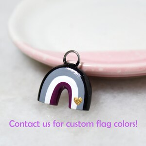 A rainbow arch charm with the asexual pride flag colors: black, gray, white, and plum purple. Text below reads: "Contact us for custom flag colors!"