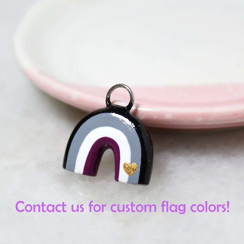 A rainbow arch charm with the asexual pride flag colors: black, gray, white, and plum purple. Text below reads: "Contact us for custom flag colors!"
