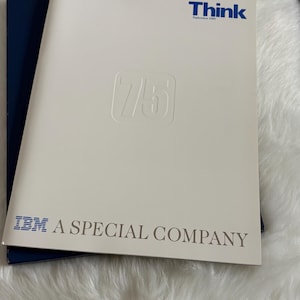 May include: A white booklet with the word "Think" in blue and "September 1989" printed above a raised "75" logo. The text "IBM A SPECIAL COMPANY" is printed in gray at the bottom. A dark blue booklet is visible beneath.