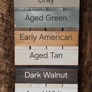 Puede incluir: Un muestrario de colores de madera con ocho colores diferentes de tinte para madera. Los colores incluyen Golden Oak, Gray, Aged Green, Early American, Aged Tan, Dark Walnut, Aged White y Aged Black. El texto est&aacute; en una fuente limpia y sans-serif.