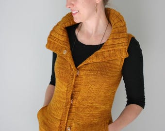 May include: A mustard yellow knitted vest with a large collar, button closure, and pockets. The vest is sleeveless and has a ribbed texture.