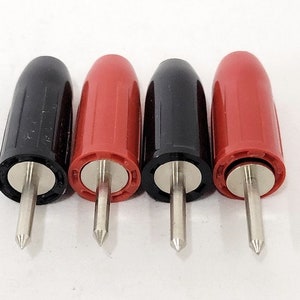 May include: Four electrical test probes with black and red insulated handles. The probes have a silver metal tip and are designed for use with multimeters or other testing equipment. The handles are smooth and cylindrical.