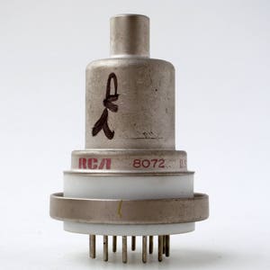 May include: A silver-colored vacuum tube with a white ceramic insulator and a red RCA logo. The tube has a black handwritten mark on the side and the text "8072... U" printed on the bottom.
