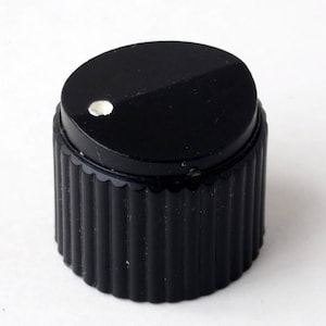 May include: Black knob with a white dot in the center and a ribbed texture around the base.