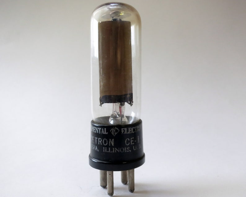 Puede incluir: Un tubo de vac&iacute;o vintage con una envoltura de vidrio transparente y una base negra. El tubo est&aacute; etiquetado "Experimental Electron CE-1, Chicago, Illinois, U.S.A."