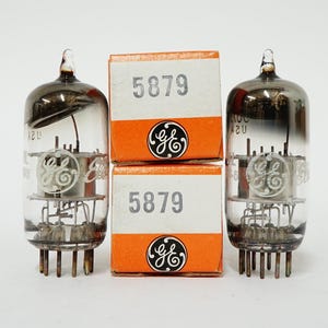 May include: Two vintage vacuum tubes with clear glass and dark tops, alongside two orange and white boxes. The boxes display the number "5879" and the GE logo. The tubes have multiple pins at the base.