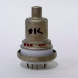 May include: A vintage vacuum tube with a metallic finish. The tube has the text "OK" and "RCA" printed on it, along with the number "4657". It features a white ceramic base and several pins at the bottom.