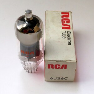 May include: A vintage RCA 6JS6C electron tube in its original box. The tube is clear glass with a silver top and a black base. The box is white with red lettering that says "RCA Electron Tube" and "6JS6C".