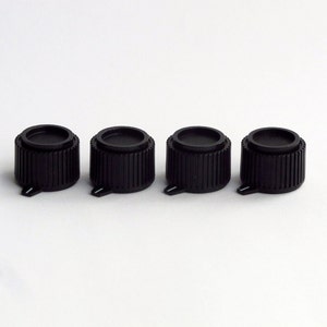 May include: Four black plastic knobs with a ridged design. The knobs have a small hole in the center and a small tab on the side.