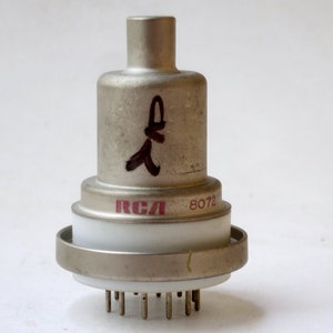 May include: A silver metal vacuum tube with a white ceramic insulator and a red RCA logo. The tube has a black handwritten inscription and the number 8072 printed on it.