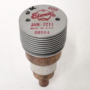 May include: A silver and copper Eimac JAN-7211 vacuum tube with a red label and the number 08594 printed on it.