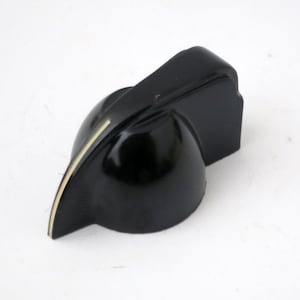 May include: A black guitar knob with a glossy finish. The knob has a curved design with a thin, off-white accent line. The knob is likely a replacement part for a musical instrument.