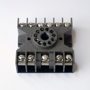 May include: Gray electrical terminal block with eight screw terminals and a round, gray, 11-pin connector. The connector has the text "MADE IN U.S.A." printed on it. The terminal block has the numbers 4, 5, 6, 7, and 8 printed on it.
