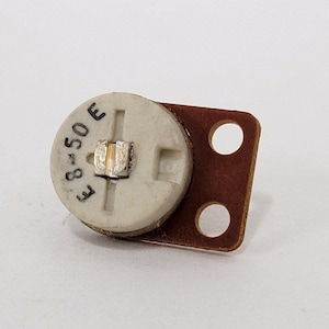 May include: A small, white, round potentiometer with a brown circuit board attached. The potentiometer has a black marking that reads "E 8-50 E".