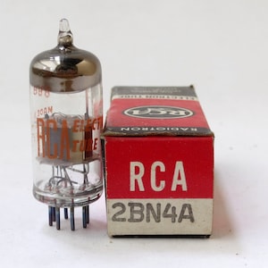 May include: A vintage RCA 2BN4A vacuum tube in its original box. The tube is clear glass with a silver top and the box is red with white lettering.
