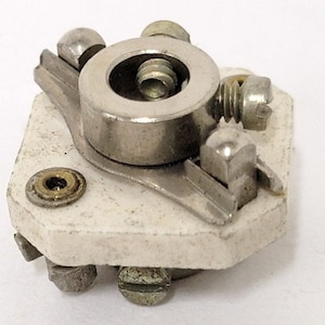 May include: A white ceramic electrical component with a silver metal rotating knob and multiple screws. The component has a round hole in the center of the knob.