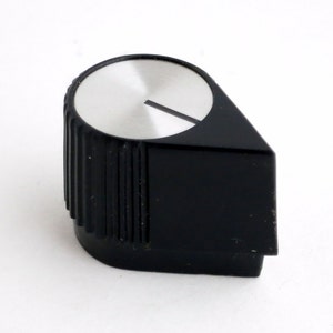 May include: A black and silver control knob with a ridged cylindrical base and a flat, angled top. The top is silver with a black line indicator. The knob is likely for audio equipment or a similar electronic device.