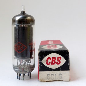 May include: A vintage CBS 6CL6 vacuum tube in its original box. The tube is made in the USA and has a black glass envelope with a red CBS logo. The box is black with a red CBS logo and the text "6CL6" printed on it.