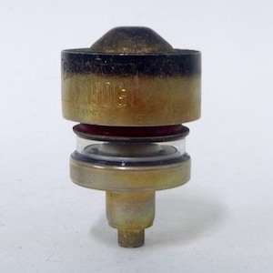 May include: A gold-colored metal valve with a black rubber seal and a clear glass cylinder. The valve has the text "150G" printed on it.