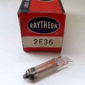 May include: A vintage Raytheon 2E36 vacuum tube in its original red and white box. The box has the Raytheon logo and the tube type printed on it.