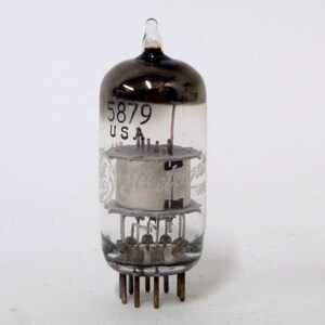 May include: A vintage 5879 vacuum tube with a clear glass body and a dark gray top. The tube has a metal base with pins and internal components visible through the glass. The text "5879 USA" is printed on the glass.