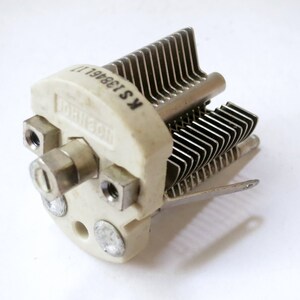 May include: A white ceramic radio tuning capacitor with a metal tuning shaft and a metal plate with the text "K513681 II" printed on it.