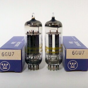 May include: Two vintage 6GU7 electronic vacuum tubes with clear glass bulbs and dark internal components. The tubes are next to their original blue boxes, which feature the Westinghouse logo and the tube type.