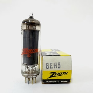 May include: A vintage Zenith 6EH5 radio tube with a glass enclosure and a black internal component. The tube is next to its original box, which is yellow and white with the Zenith logo and "6EH5" printed on it. The box also says "Radionic Tube".