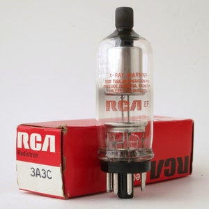 May include: A clear glass RCA vacuum tube with internal metal components and a black base, featuring red text that reads X-RAY WARNING THIS TUBE IN OPERATION MAY PRODUCE HARMFUL RADIATION UNLESS PROPERLY SHIELDED. It sits before a red RCA Radiotron 3A3C box.