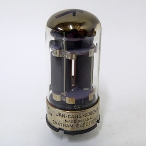 May include: A silver and glass vacuum tube with the text "JAN-CAHG-6080WB MADE IN U.S.A. CHATHAM ELECTRONIC" printed on the bottom.