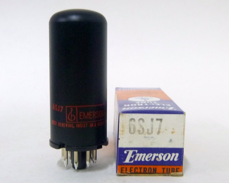 Puede incluir: Una caja blanca y negra con el texto "6SJ7 Emerson Electron Tube" en ella. Un tubo de vac&iacute;o negro con el texto "6SJ7 Emerson" en &eacute;l est&aacute; al lado de la caja.