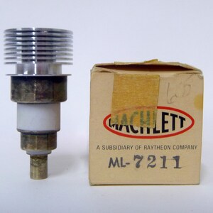 May include: A silver and brass vacuum tube with a finned heat sink, labeled "Machlett, A Subsidiary of Raytheon Company, ML-7211" in a brown cardboard box.