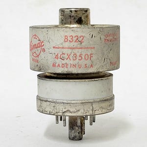 May include: A vintage vacuum tube with a cylindrical design. The tube is silver with white and red text that reads "Eimac 8322 4CX350F MADE IN U.S.A." It has a central post and multiple pins at the base.
